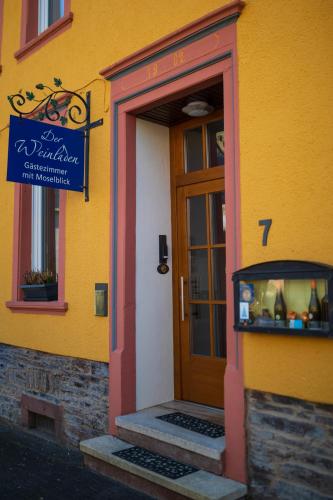 a yellow building with a door and a sign on it at Der Weinladen in Kröv