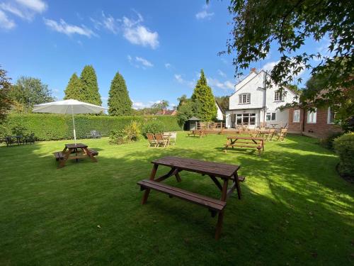 a group of picnic tables and an umbrella in a yard at Old Farm Hotel in Birmingham