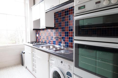 a kitchen with a sink and a washing machine at Central Cheltenham, Regency Apartment with PARKING, Cavalier Suite - Sleeps 6 in Cheltenham