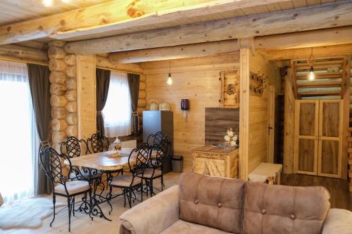 una baita di tronchi con soggiorno dotato di tavolo e sedie di Drvena Kuca RUŽA a Kopaonik