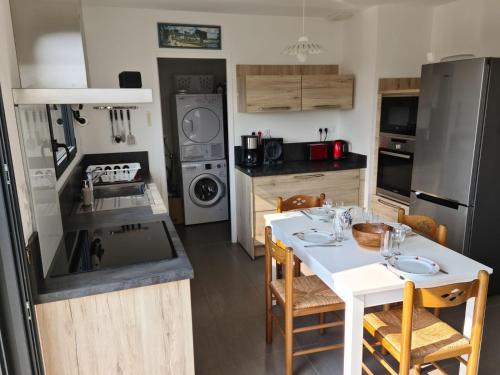 une cuisine avec une table blanche et une cuisine avec un évier dans l'établissement LES EMBRUNS MARINE, à Penpoul