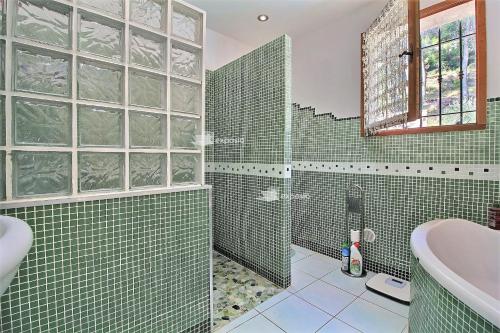 a green tiled bathroom with a shower and a sink at Les girardines in Manosque