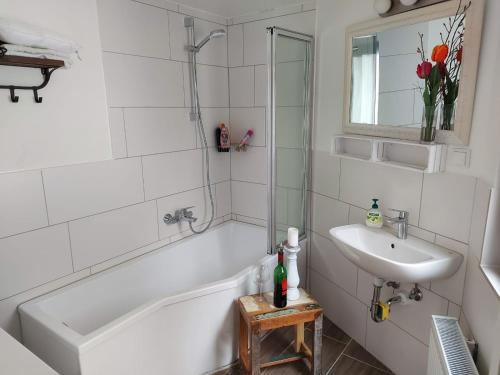 Baño blanco con lavabo, bañera y espejo en Fewo Schwalenberg, en Schieder-Schwalenberg