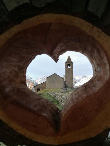 a view of a church through a heart shaped window at Rifugio Alpe San Romerio in Brusio