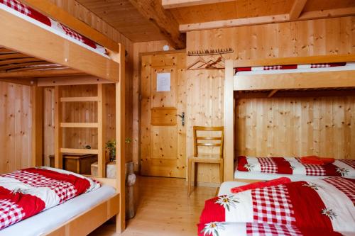 two bunk beds in a room with wooden walls at Rifugio Alpe San Romerio in Brusio