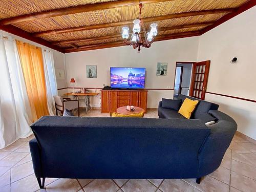 a living room with a blue couch and a tv at Palma's Place Casanova Villa #WIFI#HEATEDPOOL#RELAX in Faro