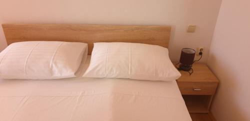 a bed with two white pillows on top of it at Apartments PHARIA in Jelsa