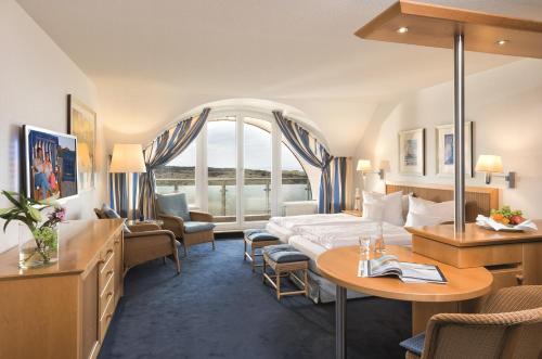 um quarto de hotel com uma cama, uma mesa e cadeiras em Strandhotel Juister Hof em Juist