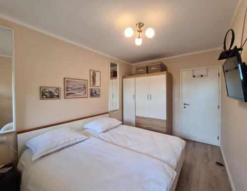 1 dormitorio con 1 cama blanca y TV en Apartman Monte Zaro Park, en Pula