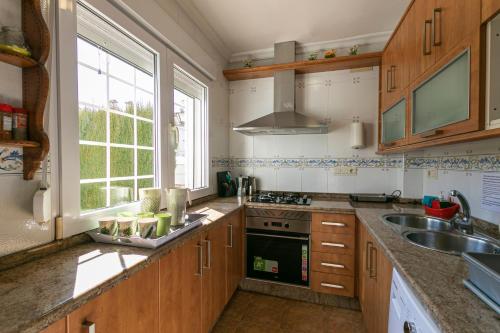 eine Küche mit Holzschränken, einem Waschbecken und einem Fenster in der Unterkunft Casa de la Vega in Cúllar-Vega