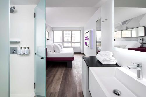 a white bathroom with a sink and a bed at YOTEL Washington DC in Washington