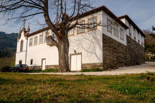 a white building with a tree in front of it at Quinta dos Poeiros in Medrões