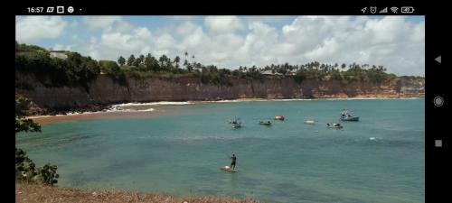 a person on a surfboard in the water with boats at CASA Praia Barra de Tabatinga NATAL RN in Nísia Floresta