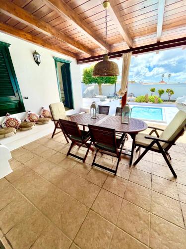 una sala da pranzo con tavolo, sedie e piscina di Luxury House Villa de Teguise a Teguise