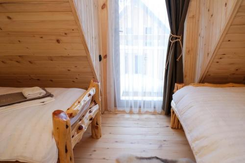 two twin beds in a room with a window at Drvena Kuca RUŽA in Kopaonik