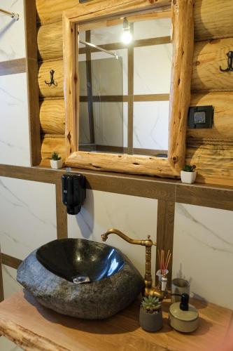 a bathroom with a stone sink and a mirror at Drvena Kuca RUŽA in Kopaonik