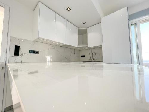 une cuisine vide avec des armoires blanches et des sols blancs dans l'établissement Villa 8 pers à 30m de la mer, à Sainte-Maxime