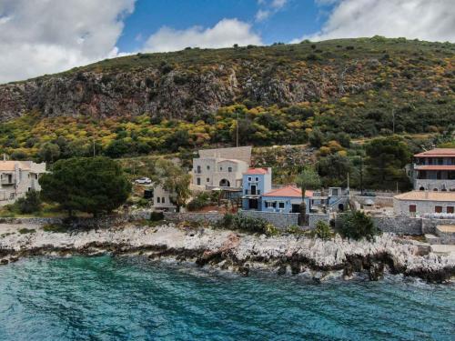 um grupo de casas numa colina junto à água em Vina's Stone House em Limeni