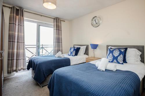 um quarto com 2 camas com lençóis azuis e brancos em Captivating 3-Bed Apartment in Grays em West Thurrock