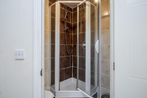 La salle de bains est pourvue d'une douche avec une porte en verre. dans l'établissement Captivating 3-Bed Apartment in Grays, à West Thurrock