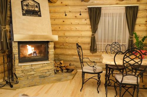 a living room with a fireplace and a table and chairs at Drvena Kuca RUŽA in Kopaonik