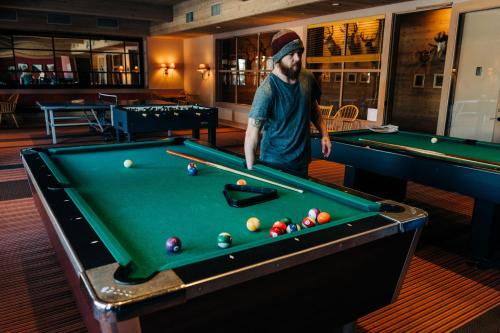 a man standing next to a pool table at Sun Mountain Lodge in Winthrop