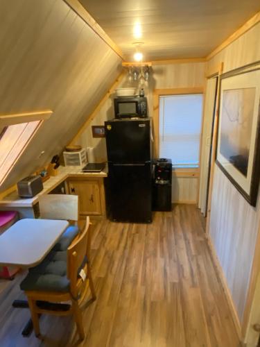 a small kitchen with a black refrigerator in a tiny house at Charming studio in-law on Great East Lake in Acton