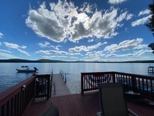 a wooden dock with a boat on the water at Charming studio in-law on Great East Lake in Acton