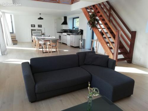 a living room with a black couch and a table at Les écuries du Nevez in Plonéour-Lanvern
