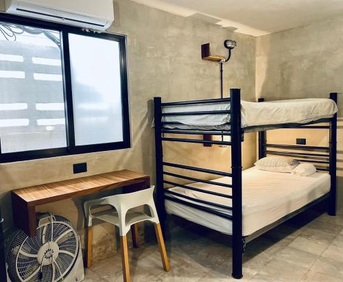a bedroom with bunk beds and a desk and a window at Moloch Hostel & Suites in Cancún