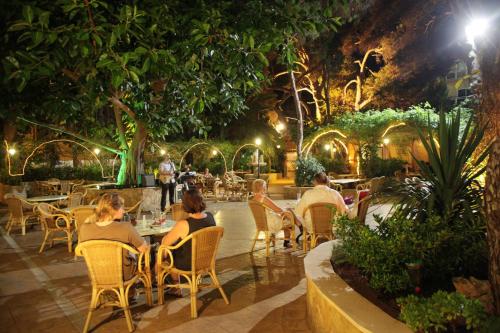 people sitting at tables in a garden at night at Hotel Baviera in Cala Ratjada