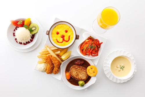 a table topped with plates of food and a glass of orange juice at Shin Osaka Esaka Tokyu REI Hotel in Suita