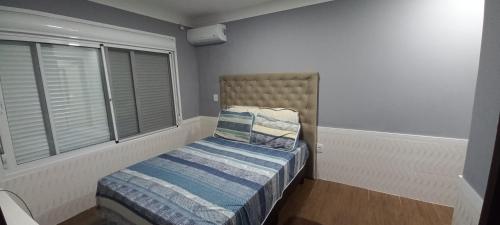 niewielka sypialnia z łóżkiem i oknem w obiekcie Casa confortável com piscina w mieście Tramandaí