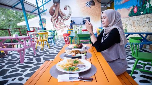 una mujer sentada en una mesa con un plato de comida en Baron Lighthouse Cottage & Eatery, en Baron