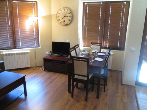 a dining room with a table and a clock on the wall at Comfort Private Apartments in Bansko