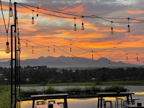 a sunset with tables and lights over a body of water at Kaloka Airport Hotel in Labu Sumbawa