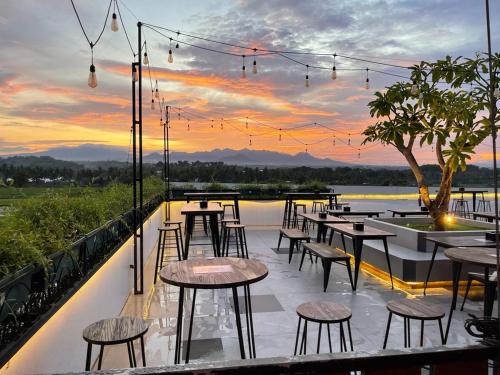 a row of tables and chairs on a balcony with a sunset at Kaloka Airport Hotel in Labu Sumbawa