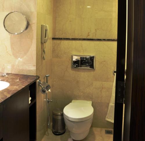 a small bathroom with a toilet and a phone at Adarsh Hamilton in Bengaluru