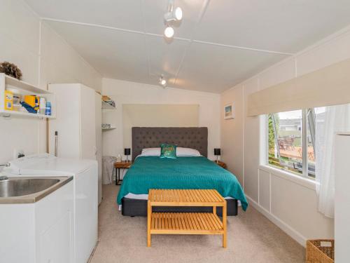 1 dormitorio con 1 cama con mesa y lavamanos en Bach Life on Seabreeze - Whangamata Holiday Home, en Whangamata