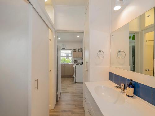 Un baño blanco con lavabo y espejo. en Bach Life on Seabreeze - Whangamata Holiday Home, en Whangamata