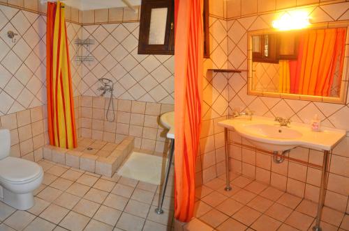 a bathroom with an orange shower curtain and a sink at Villa Takis on Pelekas beach Apartment A with private garden and sea view in Pelekas