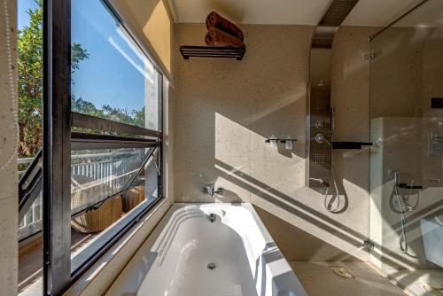 a bathroom with a bath tub and a window at SaffronStays Hillside Harriers, Lonavala - A Frame chalets with bathtub for couples in Lonavala