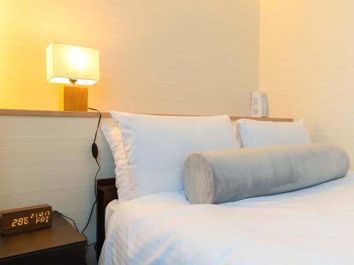 a bed in a hotel room with a pillow on it at Kyoto inn Mio in Kyoto