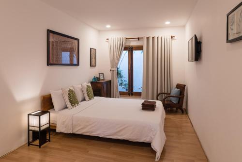 ein Schlafzimmer mit einem weißen Bett und einem Fenster in der Unterkunft The Bohome in Quy Nhon