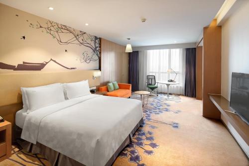 Holiday Inn Chengdu High-Tech Center, an IHG Hotel في تشنغدو: غرفة فندق بسرير كبير وتلفزيون