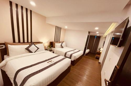 a hotel room with two beds and a television at Villa Camellia in Da Lat