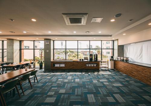 a restaurant with tables and chairs and windows at Hotel Sweet Castle Jeju Hamdeok in Jeju