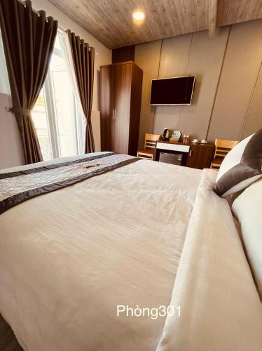 a bedroom with a large white bed with a television at Villa Camellia in Da Lat