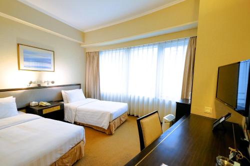 a hotel room with two beds and a flat screen tv at South Pacific Hotel in Hong Kong