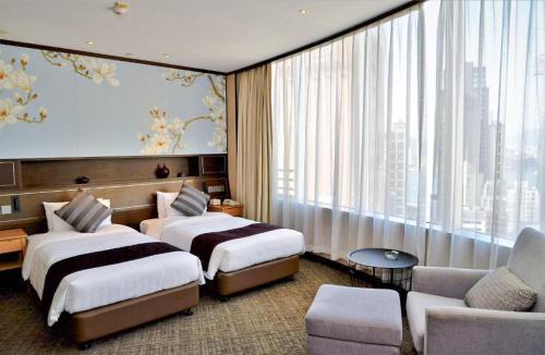 a hotel room with two beds and a couch at South Pacific Hotel in Hong Kong